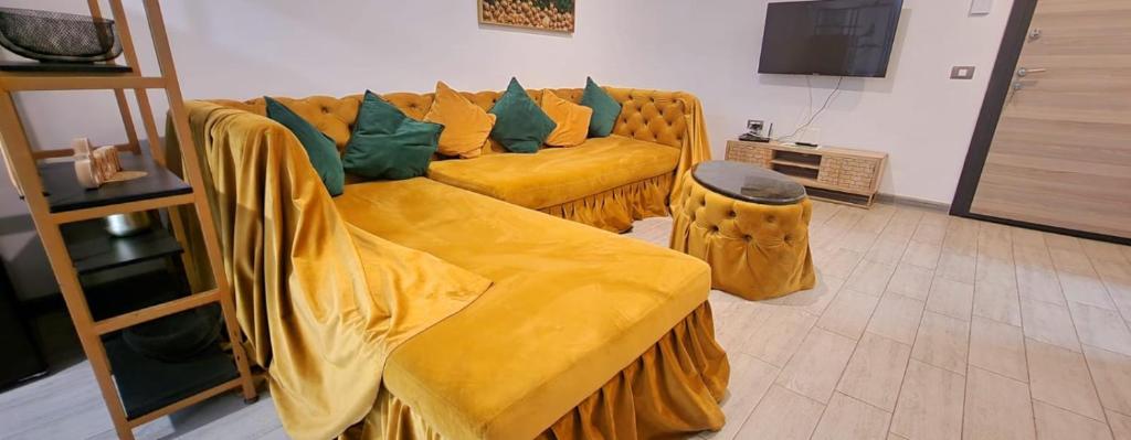 a living room with a yellow couch with green pillows at Azizi Luxury Apartments - Beach Pool & Spa Resort in Mamaia Nord
