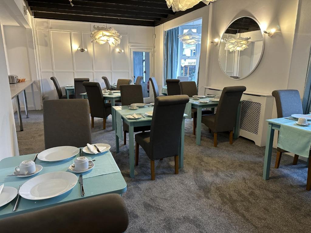 Tintagel Arms Bed and Breakfast في تينتاجيل: غرفة طعام مع طاولات وكراسي ومرآة