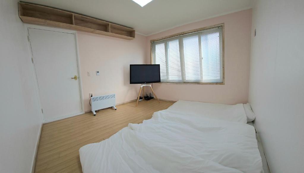 a bedroom with two beds and a flat screen tv at 스테이 노랑 stay norang in Daegu