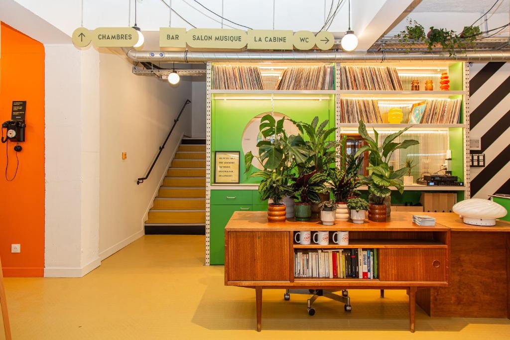 een kamer met een boekenplank met boeken en planten bij OLDEGAR Hôtel in Nantes