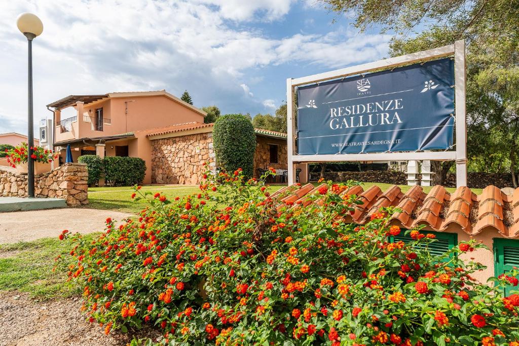 a sign in front of a house with flowers at Residenze Gallura in San Teodoro