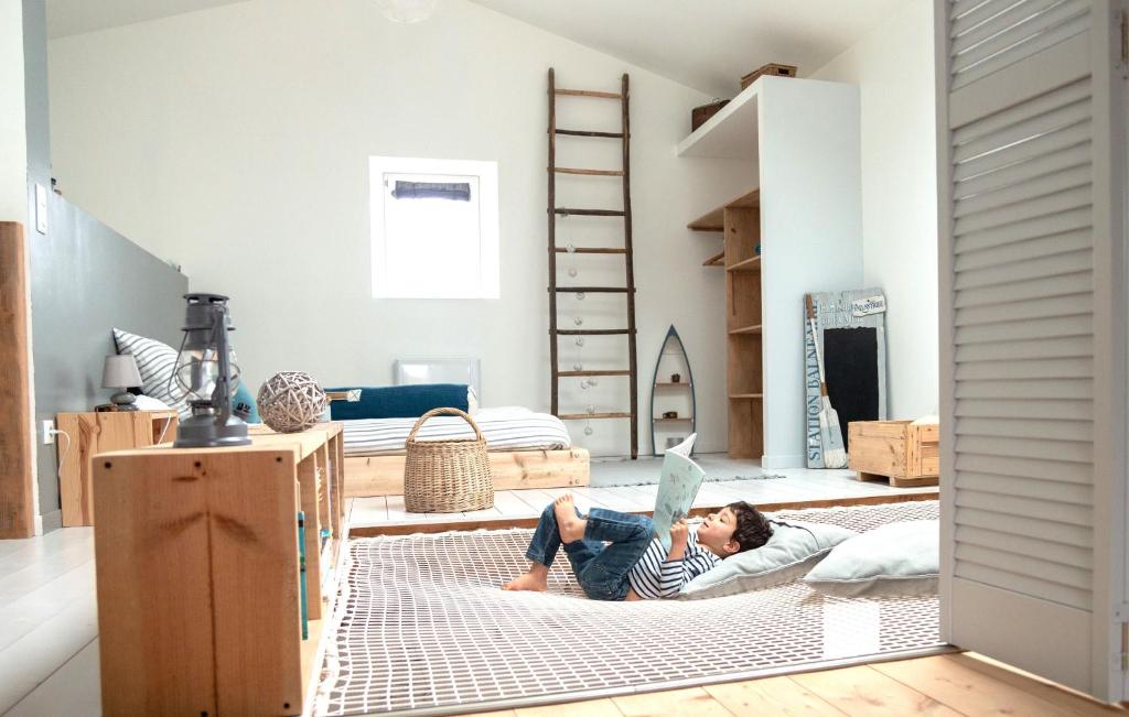 a young boy laying on a bed in a room at Loft avec filet d'habitation suspendu géant proche mer in Bouin
