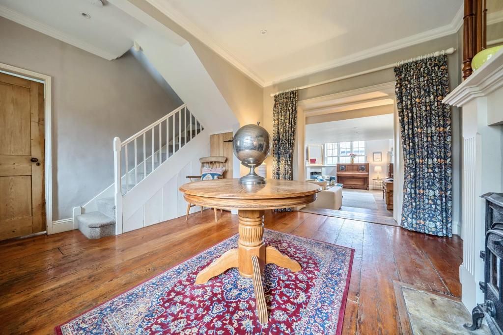 a living room with a table and a staircase at Old School House in Burnham Market