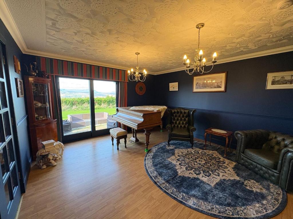 een woonkamer met een piano, een bank en een kleed bij Abalone Accommodation in Culbokie