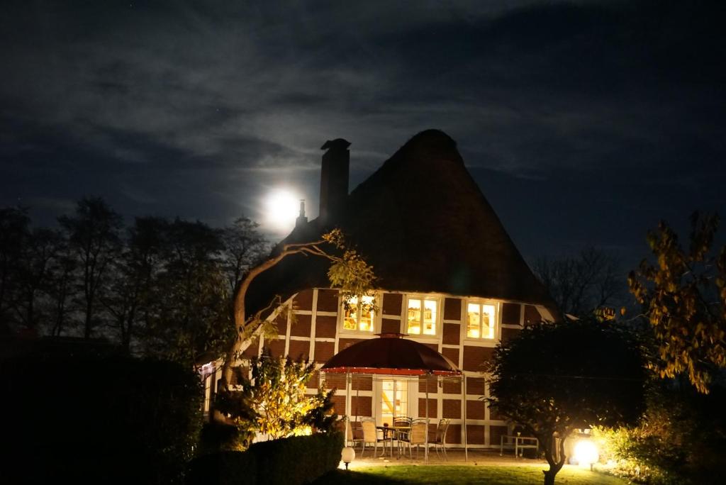 una casa con techo de paja por la noche en Kamin Ofen Wohnung -Altes Landhaus Oste- 2 Schlafzimmer, Terrasse, Grill, Küche, Bad, WLAN, nah am Nordsee Strand, en Hemmoor