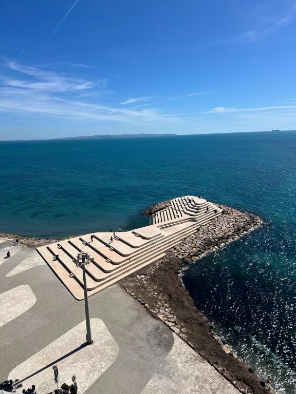 a wooden bench sitting on the side of the ocean at Azure Dream Apartment in Durrës