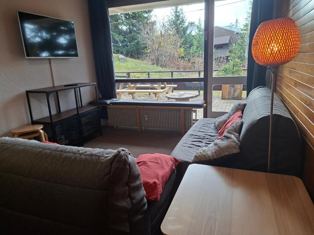a living room with a couch and a large window at Chamrousse 1750 - Le Taillefer - Appartement classé 3 étoiles in Chamrousse