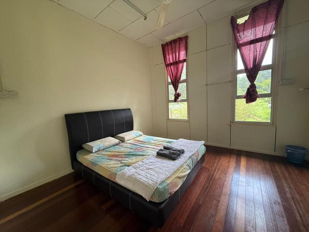 ein Schlafzimmer mit einem Bett und zwei Fenstern in der Unterkunft Mahua Lodge and Campsite in Tambunan