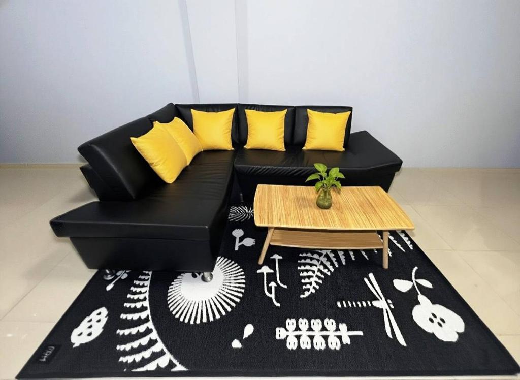 Sofá negro con almohadas amarillas y mesa en BirdHostel Chiangrai, en Chiang Rai