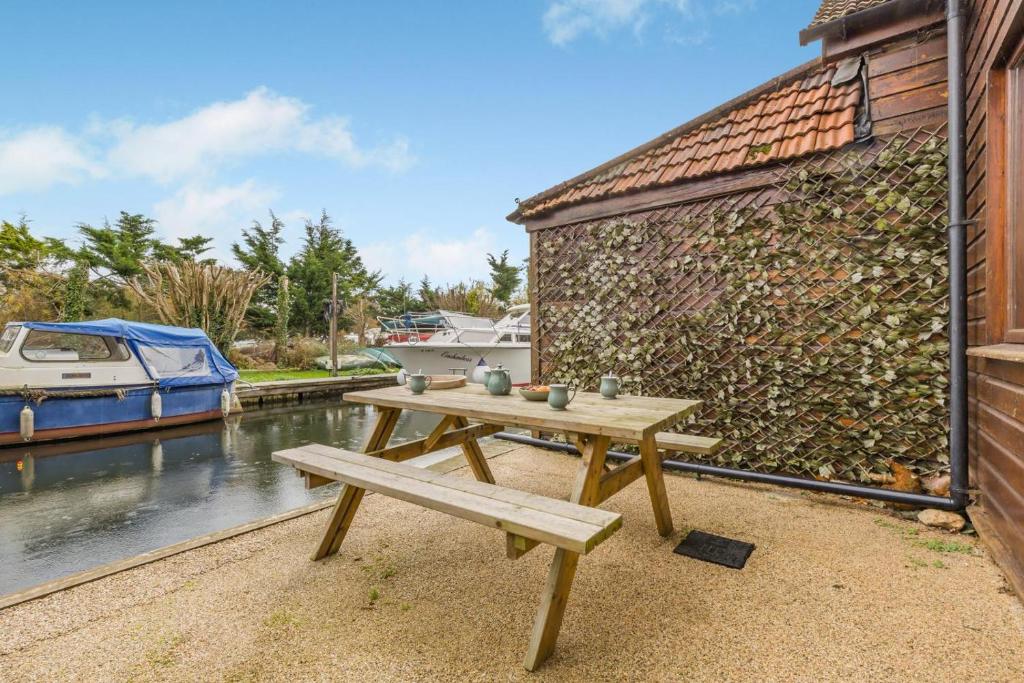 Una mesa de picnic de madera junto a una pared con un barco. en 2 Bed in Smallburgh oc-h33734, en Dilham