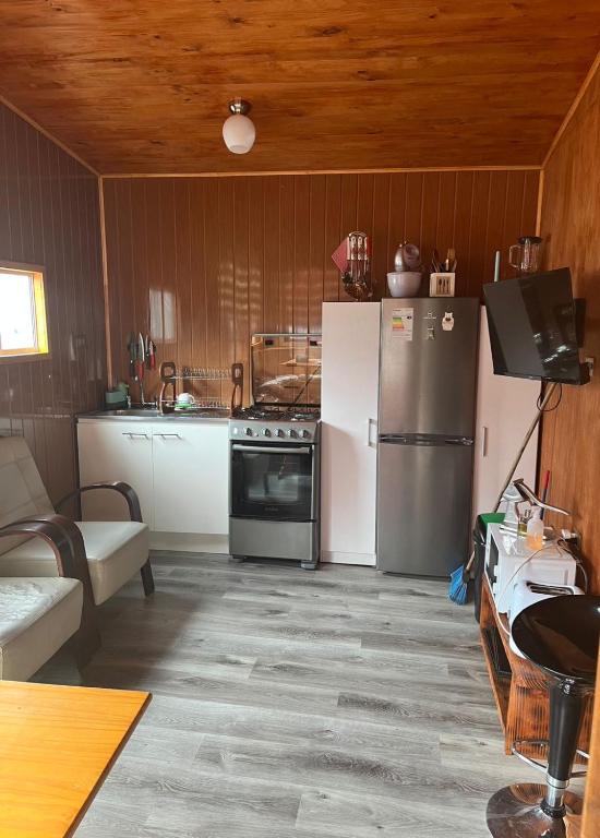 a kitchen with a stove and a refrigerator at Cabañas Sofía in Puerto Cisnes