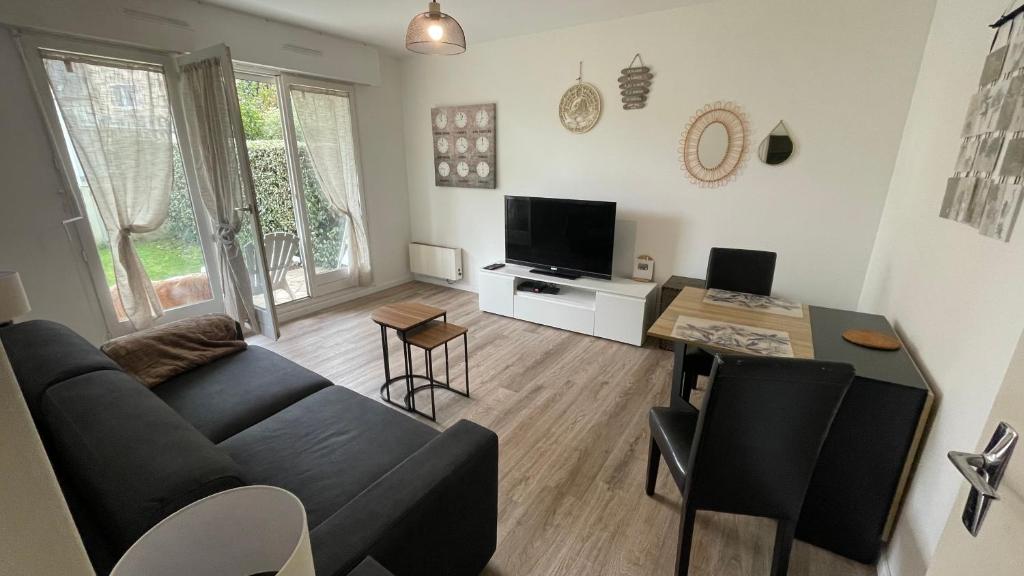 ein Wohnzimmer mit Sofa und Tisch in der Unterkunft Studio avec jardin centre ville Cabourg La Roseraie in Cabourg
