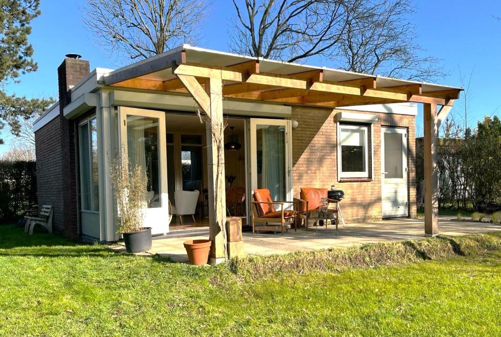 una casa con pergolato in legno su un patio di Vakantiebungalow Vrijzicht a Kortgene
