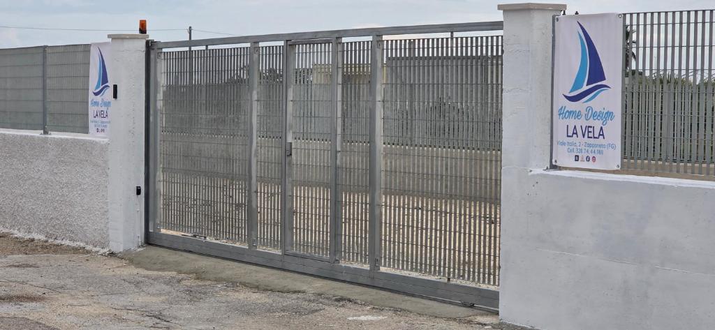 a gate in a fence with a sign on it at Home Design La Vela in Zapponeta
