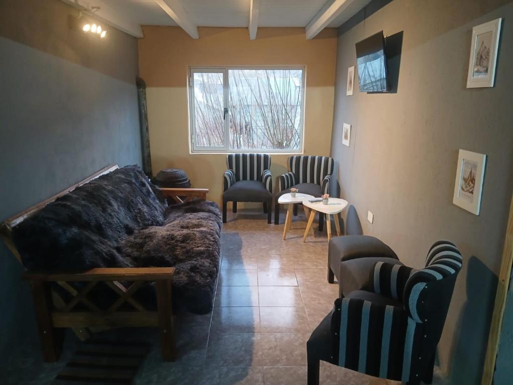 a living room with a couch and chairs and a window at El Kamaruco Hostel in El Chalten