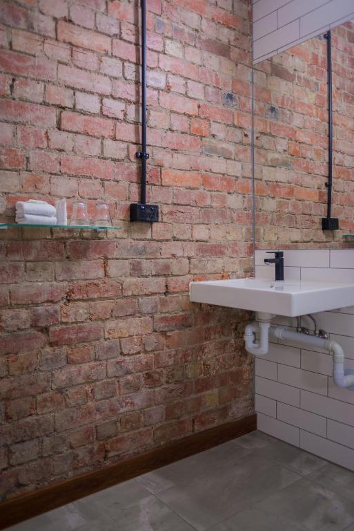 a bathroom with a brick wall and a white sink at Best Western Melbourne City in Melbourne