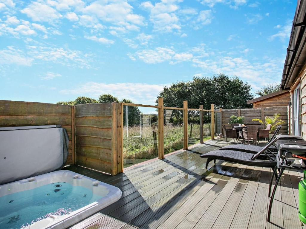 ウエストワード・ホーにある2 Bed in Westward Ho 41132のホットタブ、テーブル、椅子付きのデッキが備わります。