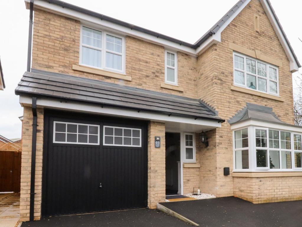 a detached house with a black garage at Mellings Place in Carnforth