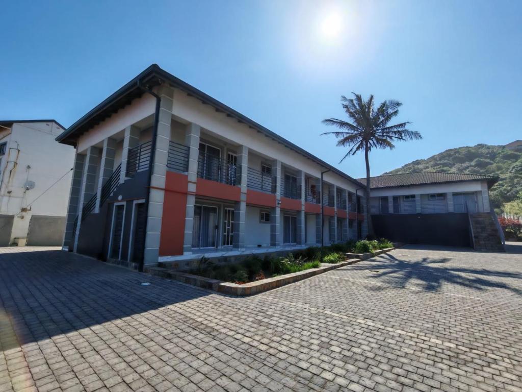 a building with a palm tree in front of it at Modern Beachfront Escape in La Mercy in La Mercy