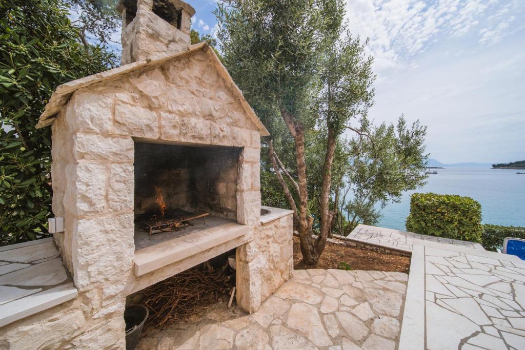 a stone fireplace sitting on a patio next to the water at Apartments by the sea Lumbarda, Korcula - 135 in Lumbarda