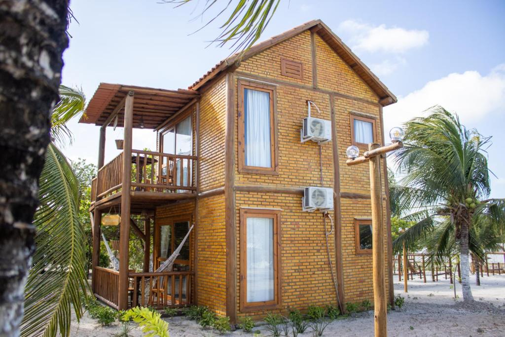a bamboo house with a balcony on a beach at Sitio Meu Refúgio Paracuru in Paracuru