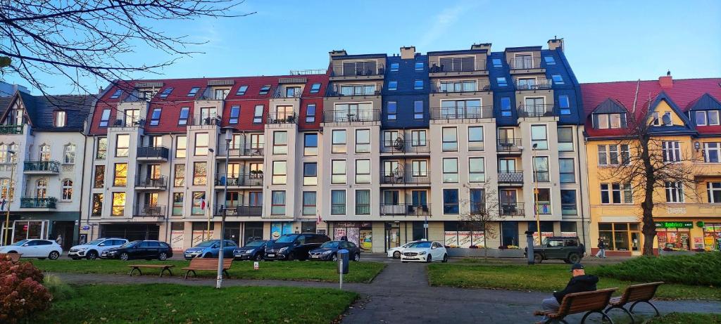 un hombre sentado en un banco frente a un edificio en Kapi Royal Apartament, en Świnoujście