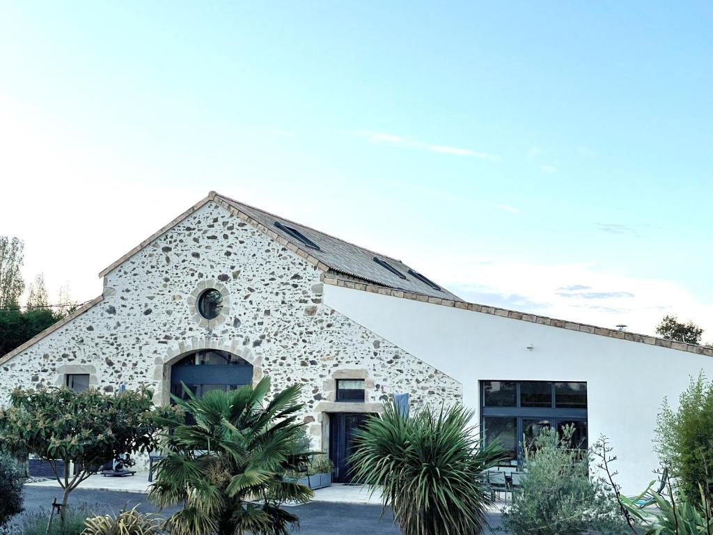 a stone building with palm trees in front of it at "La Petite Félixière" à 25 min du Puy du Foù, 10 min de Cholet, et 35 min de Nantes in Saint-André-de-la-Marche