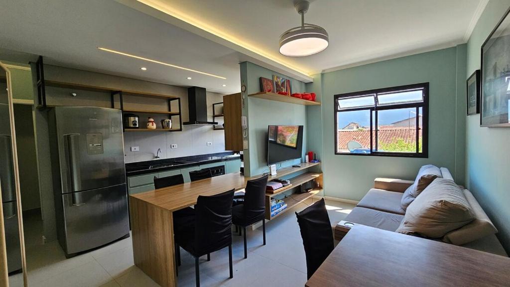 a kitchen and living room with a couch and a table at Apartamento com 1 suíte, 1 lavabo, 1 vaga a 70m da Praia in Praia Grande