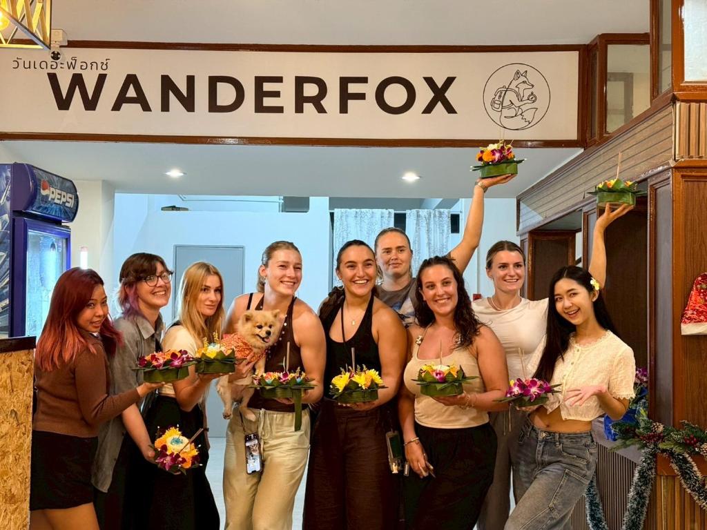un gruppo di persone in piedi sotto un cartello con dei fiori di WanderFox a Chiang Mai