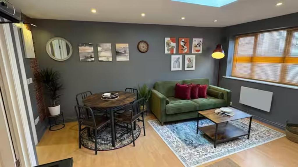 ein Wohnzimmer mit einer grünen Couch und einem Tisch in der Unterkunft Watford High Street apartment with kitchen & sofa bed in Watford