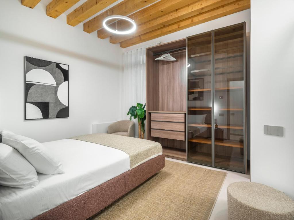 a white bedroom with a bed and a chair at Palazzo Degli Eletti R&R in Venice
