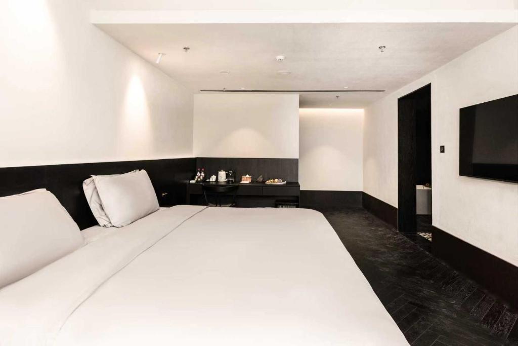 een slaapkamer met een groot wit bed en een televisie bij 烟台朝阳文保艺术酒店 in Yantai