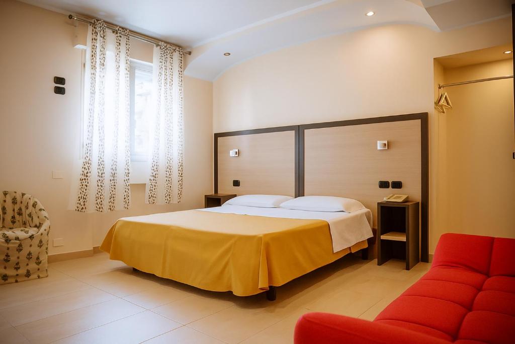 a bedroom with a large bed and a red couch at Hotiday Conegliano in Conegliano