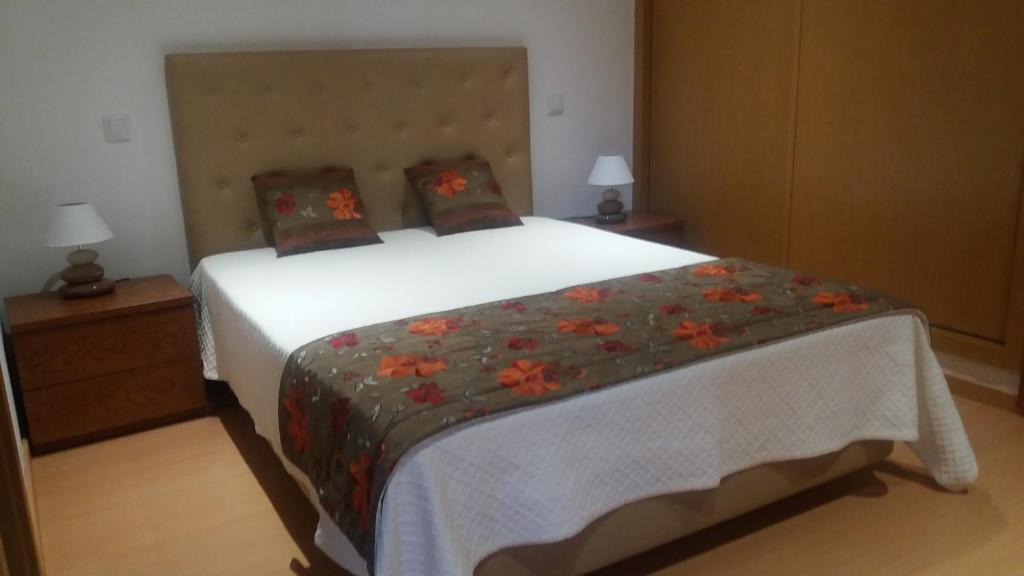 a bedroom with a large white bed with flowers on it at Casa De Campo Cantinho Da Serra in Cortelha