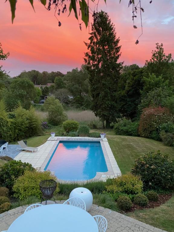 a swimming pool in a yard with a sunset at Maison d'hôte Yourehome 2 belles chambres à louer individuellement dans un écrin de verdure in La Hulpe