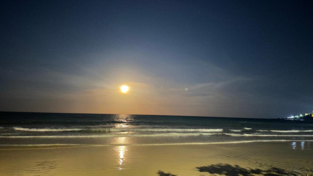 a beach at night with the sun rising over the ocean at Orla Pousada & Café in Parnamirim