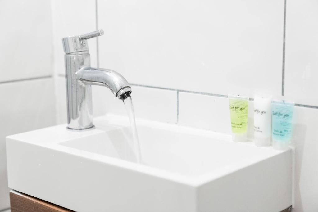 a bathroom sink with water running from a faucet at Modern Apartment - Wolverhampton Centre - Fast WiFi - Netflix 12AC in Wolverhampton
