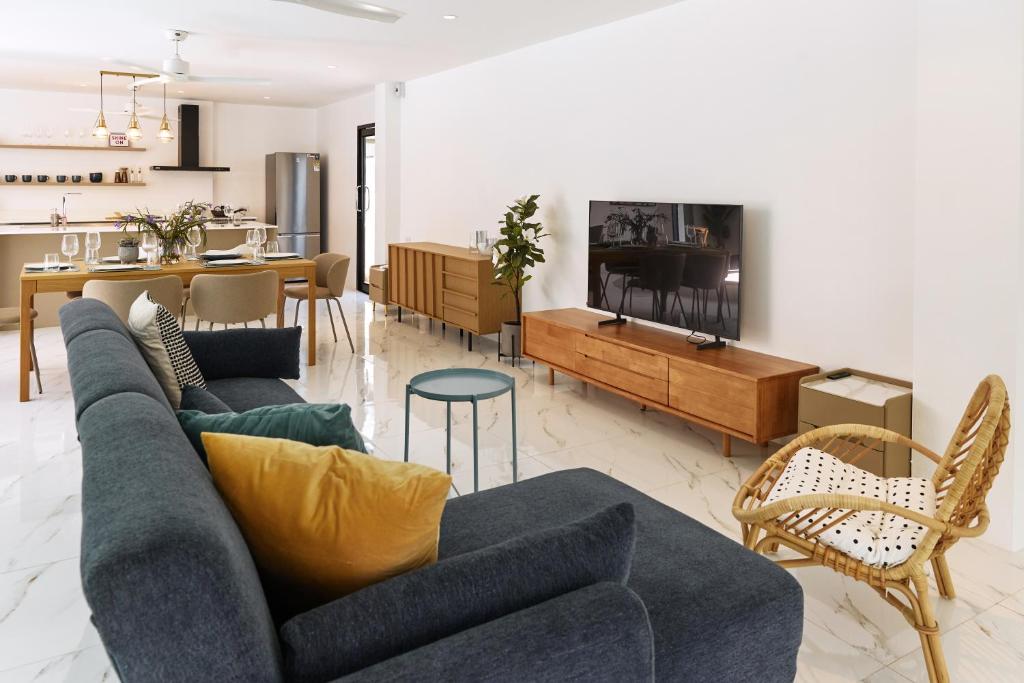a living room with a blue couch and a kitchen at Modern Villa 4-BR, Breeze - 10 min walk to NaiYang beach in Nai Yang Beach
