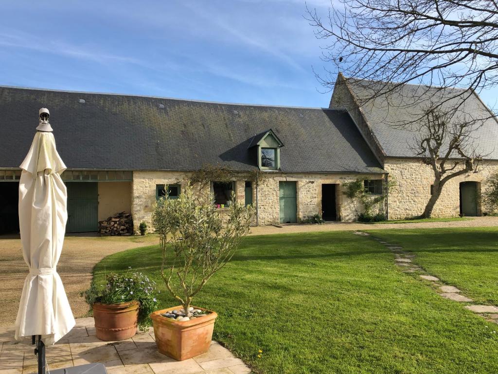 a large stone house with a white umbrella in front of it at Studio des Perriots in Englesqueville-la-Percée