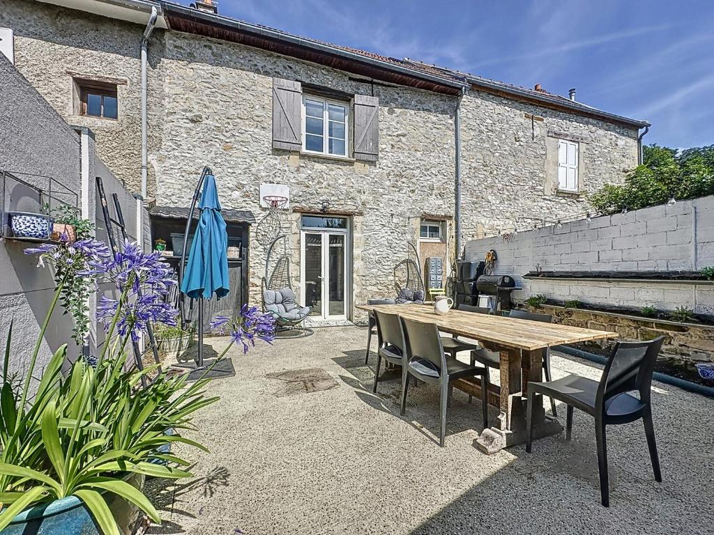 eine Terrasse mit einem Holztisch und Stühlen vor einem Gebäude in der Unterkunft pleasant old and comfortable little house in Apremont