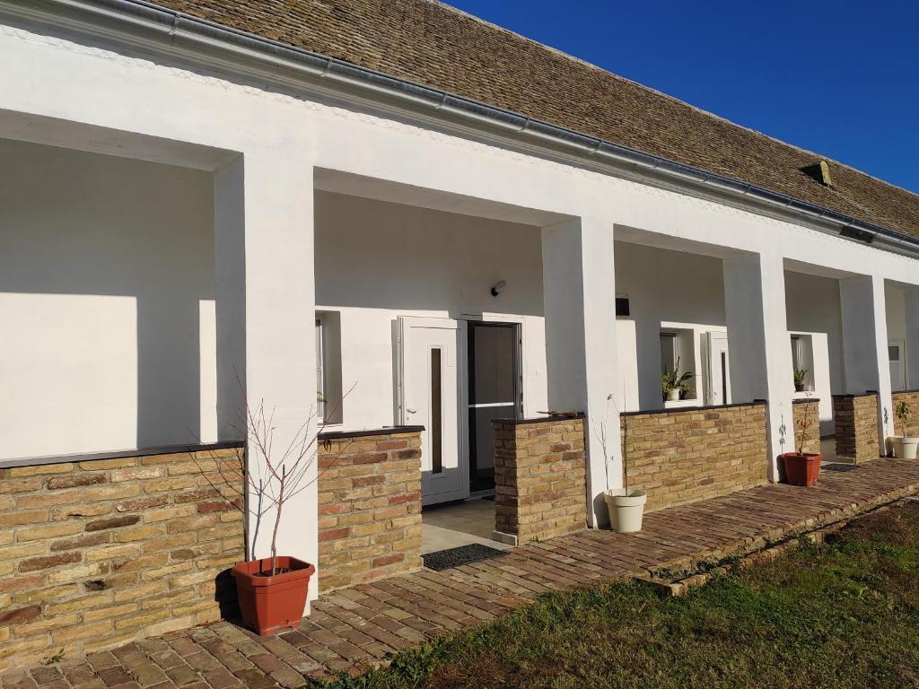 a white house with a brick wall and a porch at Sobe i apartman Berecz in Kopačevo