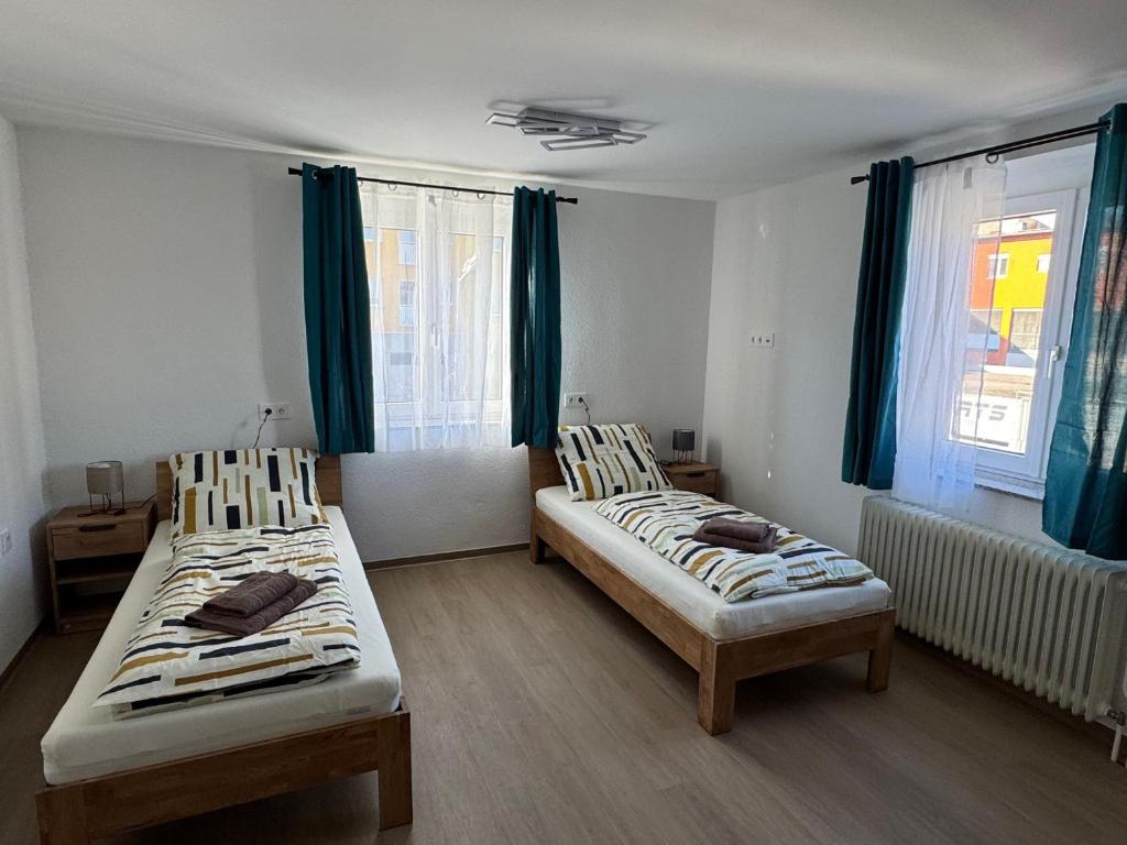 two beds in a room with blue curtains at Stadtquartier Völkermarkt in Völkermarkt