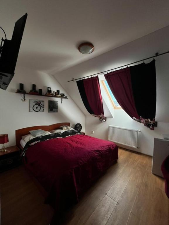 a bedroom with a red bed and two windows at Penzión Korytnačka in Námestovo