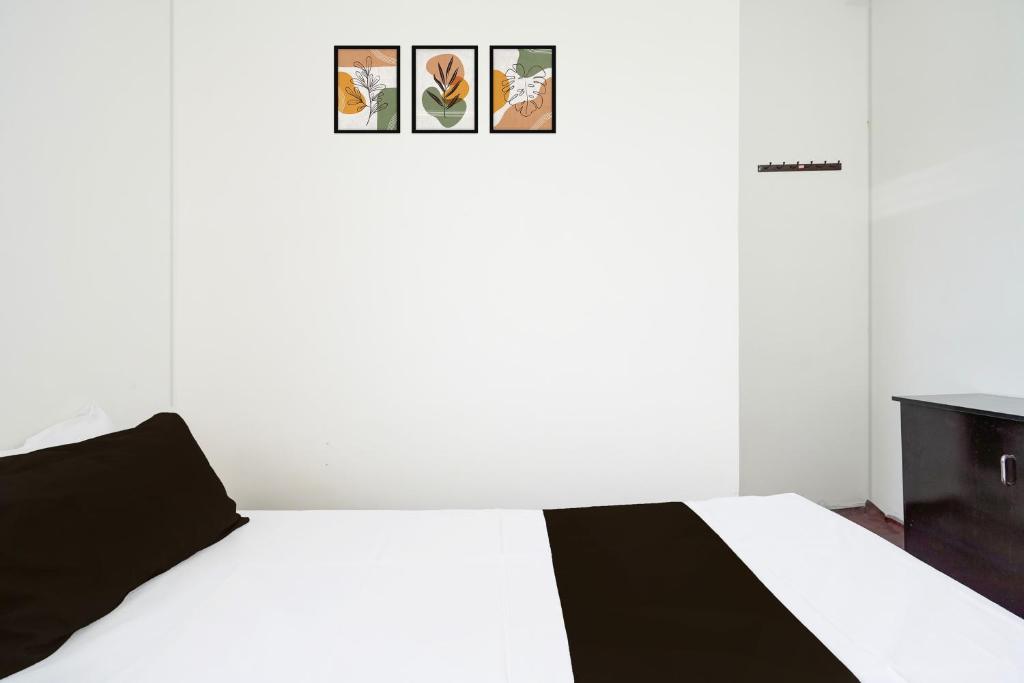 a bedroom with a white bed and three pictures on the wall at SPOT ON Ap Logde in Māharjhari