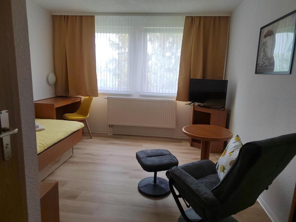 a small room with a bed and a chair at Pension Schachtblick in Bleicherode