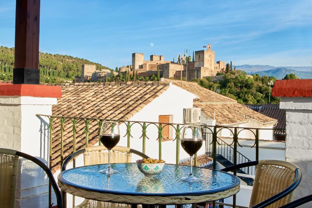 a table with two glasses of wine on a balcony at Oripando Private Rooms in Granada