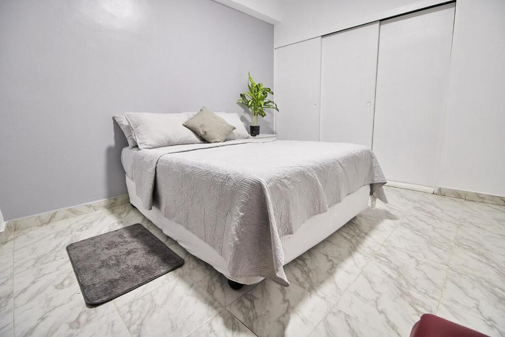 una camera da letto bianca con un letto e una pianta in vaso di La Reserve a Porlamar