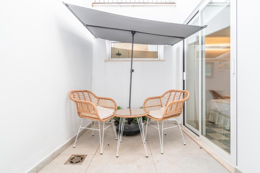 a table and chairs under an umbrella in a room at Can 32 Apartamento 1 habitación in Pollença