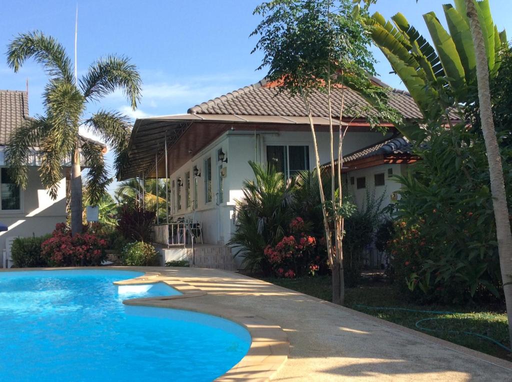 a house with a swimming pool in front of a house at Nuch's Apple Guest House in Si Bun Ruang