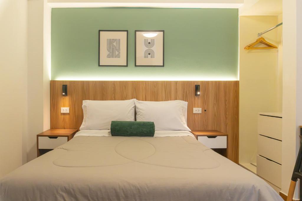 a bedroom with a bed with a green pillow on it at Majhu Hostal in Tacna